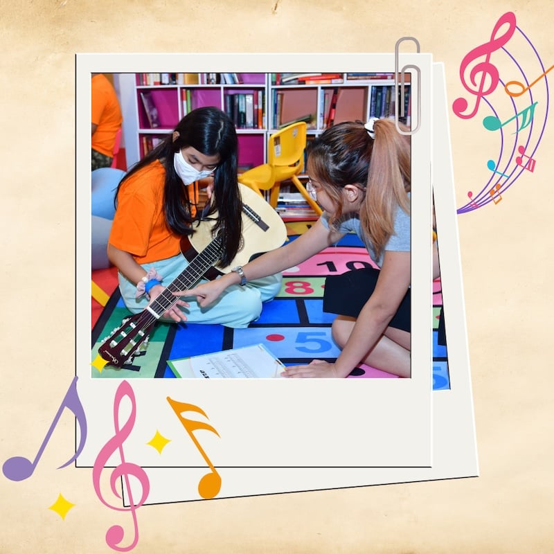 A teacher (right), instructing student (left) how to play the guitar.